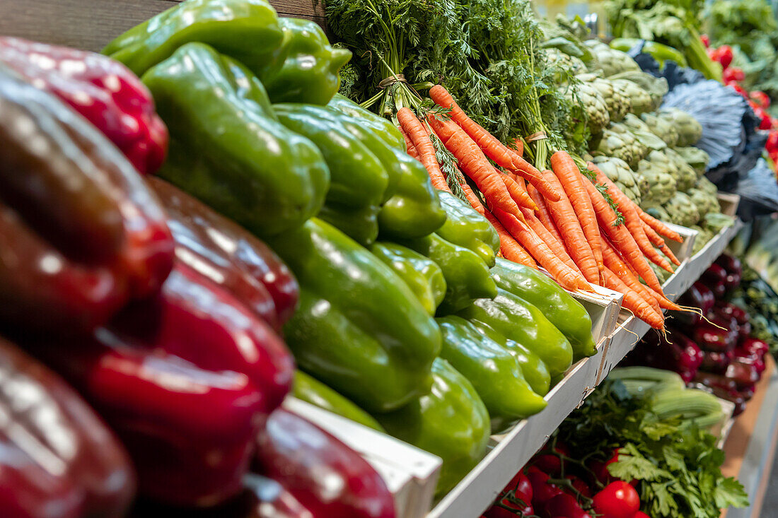 Vibrant display of fresh vegetables at a local market stall, featuring bell peppers, carrots, and leafy greens