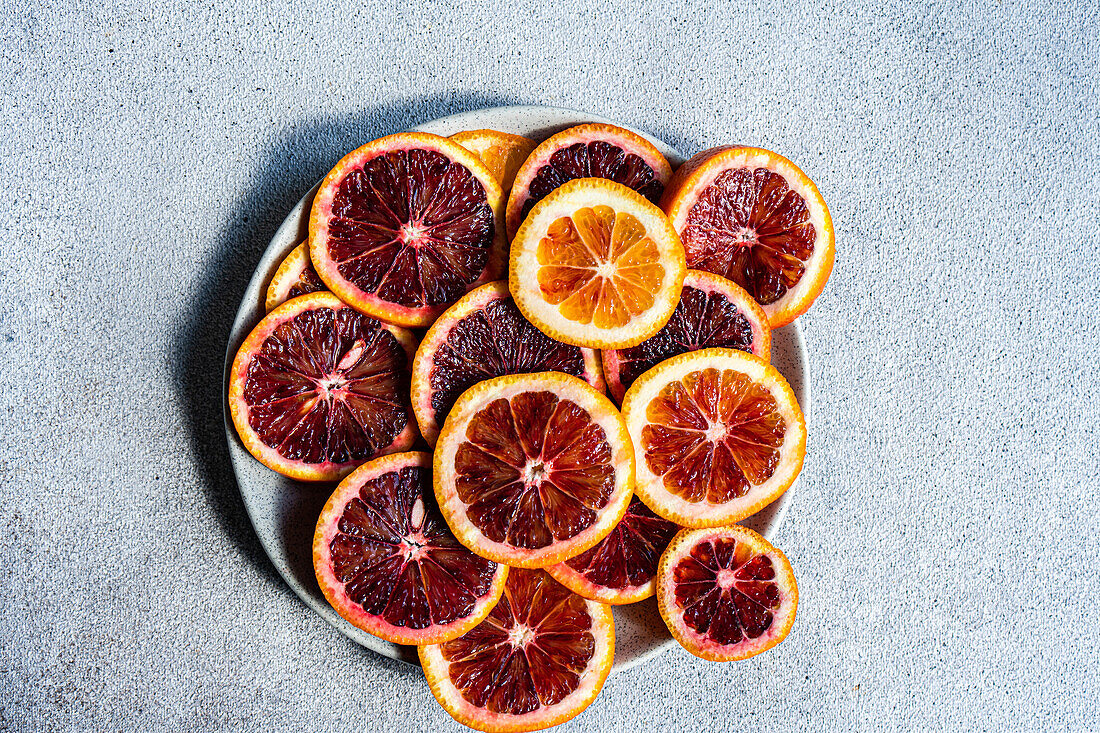 Top view of vibrant Sicilian blood orange slices arranged on a circular plate, showcasing their juicy segments and rich color contrast.