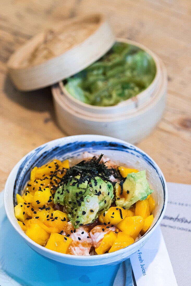 From above of delicious poke dish in bowl served on wooden table in restaurant