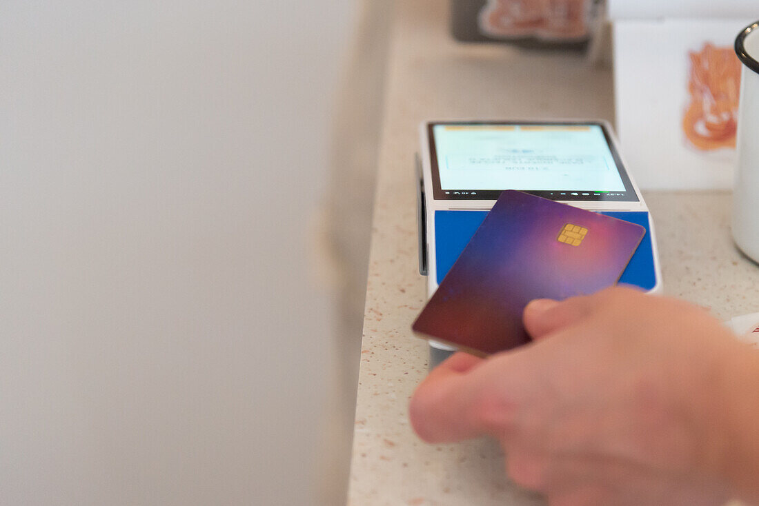 Cropped unrecognizable person using a credit card for payment at a coffee shop