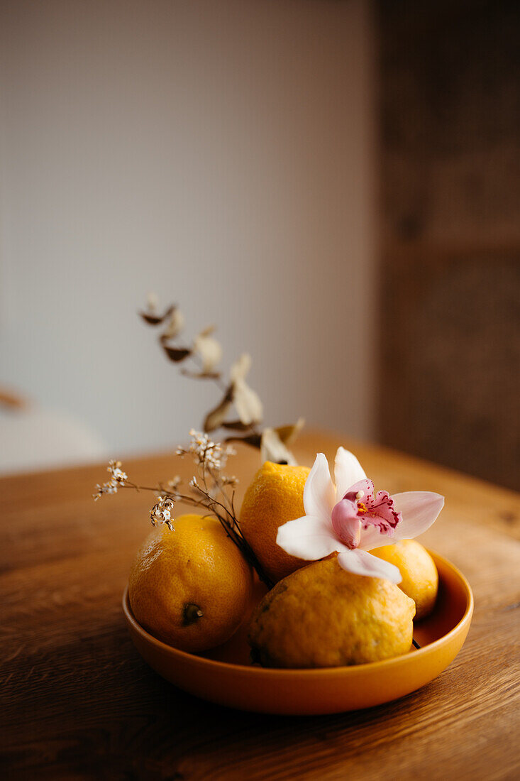 Ein heiteres Stillleben mit frischen Zitronen in einer Schale und einer zarten Orchideenblüte