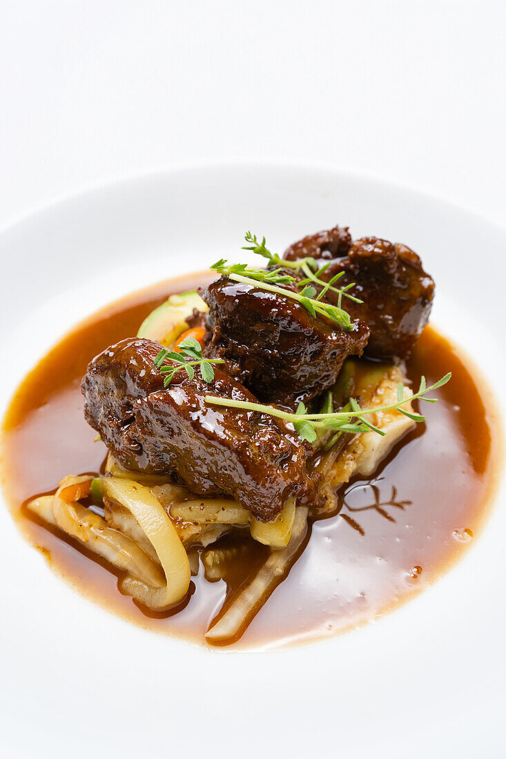 Succulent pork cheeks with a rich Pedro Ximenez reduction, served on a bed of sauteed vegetables, garnished with fresh sprouts.