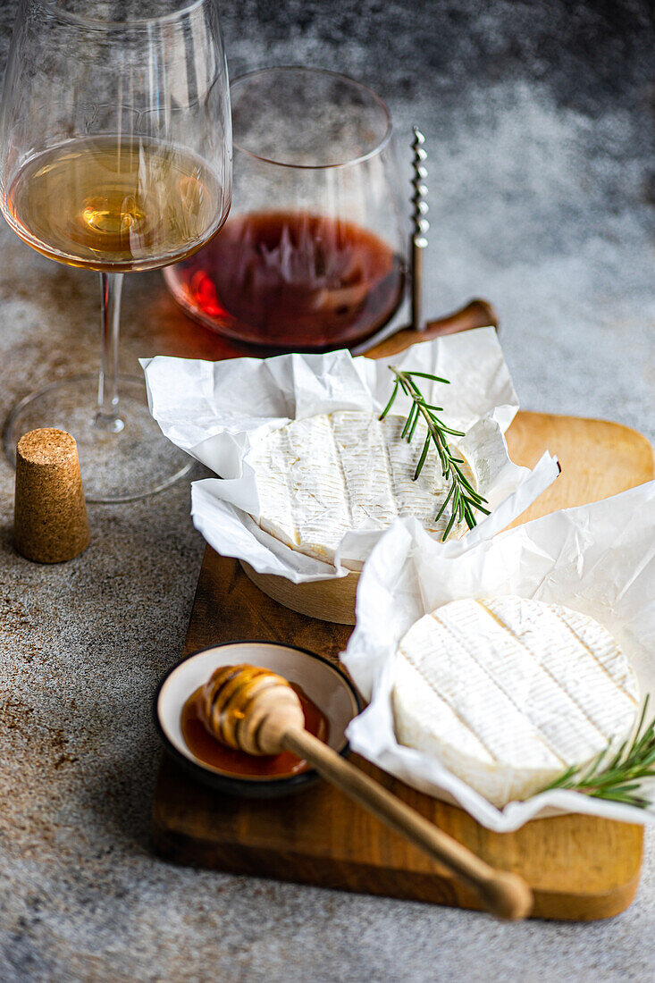 An exquisite display of Brie cheese complemented by honey, rosemary, and a pairing of red and white wine.