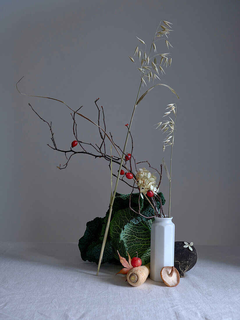 A tasteful arrangement featuring savoy cabbage, a black radish, and tiny red crab apples, enhancing the artistic allure of this still life set against a neutral background.