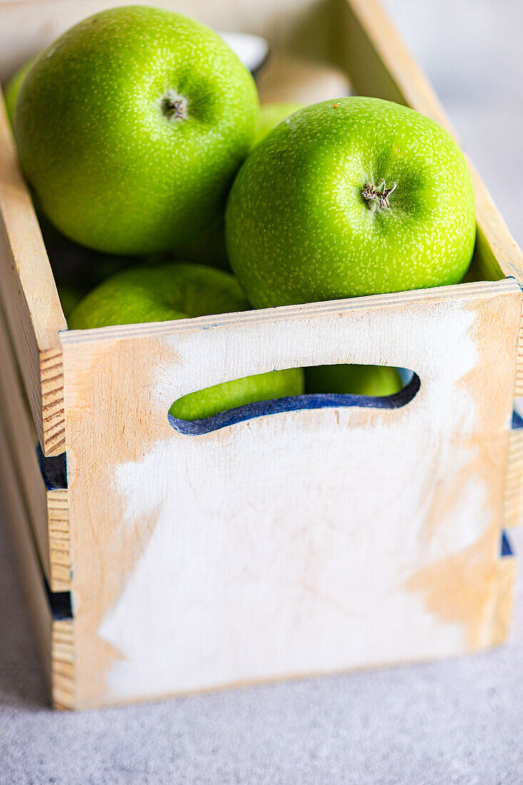 Bright green apples showcased in a wooden crate, providing a vivid display of freshness and natural appeal, perfect for a healthy lifestyle theme