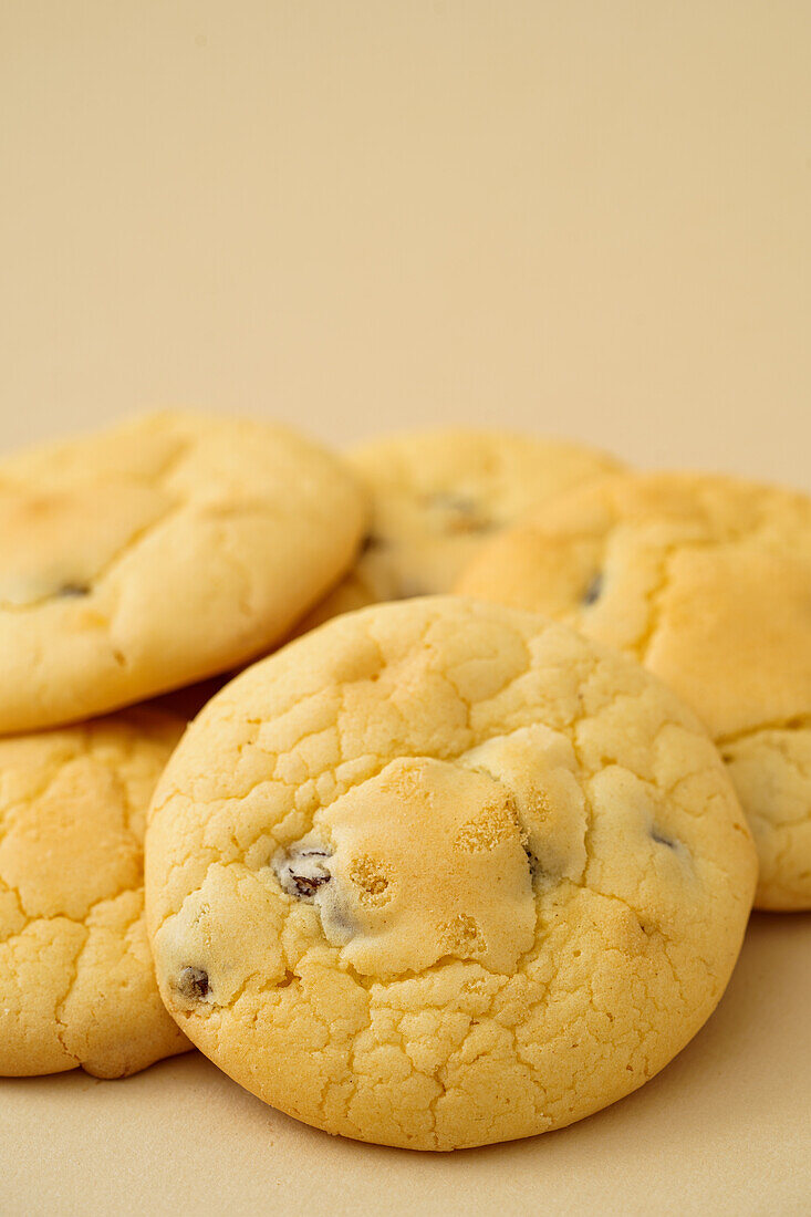 Freshly baked homemade raisin biscuits displayed on a neutral beige background, ideal for a sweet treat.