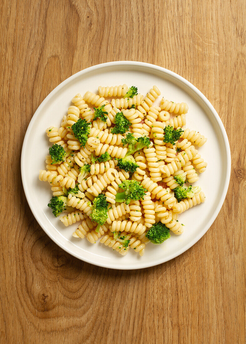 Draufsicht auf ein köstliches Gericht mit Fusilli-Nudeln und leuchtend grünen Brokkoliröschen, präsentiert auf einem weißen Teller