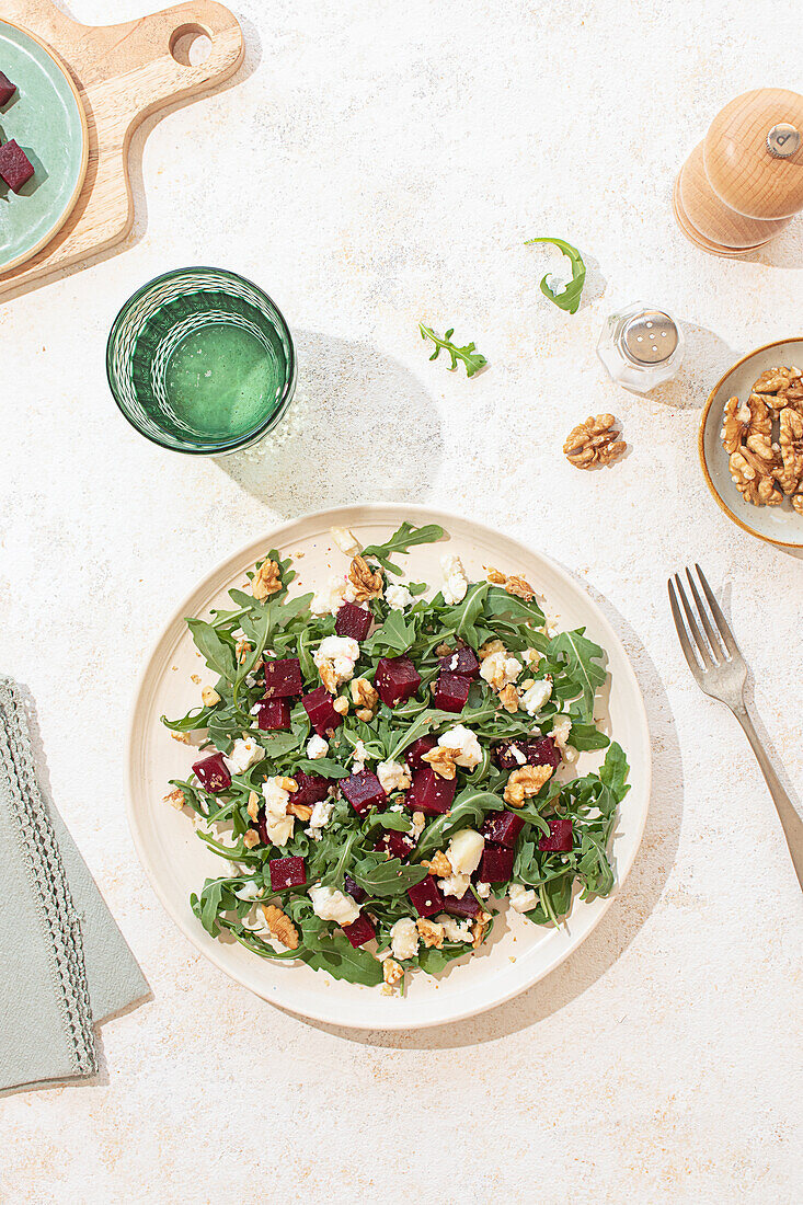 A fresh arugula salad with goat cheese, walnuts, and beetroot on a beige plate. Natural light highlights the vibrant colors and textures, creating a fresh and inviting atmosphere