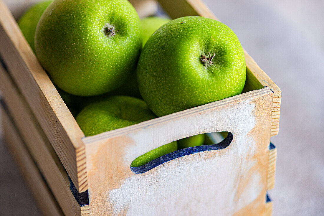 Kräftig grüne Äpfel, frisch und reif, sind ordentlich in einer rustikalen Holzkiste verpackt und vermitteln ein Gefühl von gesunder, natürlicher Frische