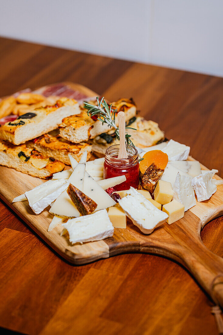 An inviting cheese board laden with an assortment of cheeses, crackers, and a jar of red jam, ready for a gourmet tasting