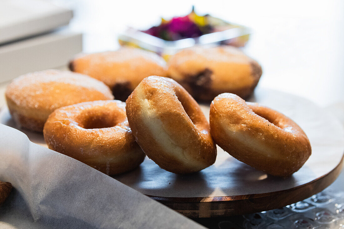 Various vegan sweet donuts and cakes on wooden tray placed on counter in bakery