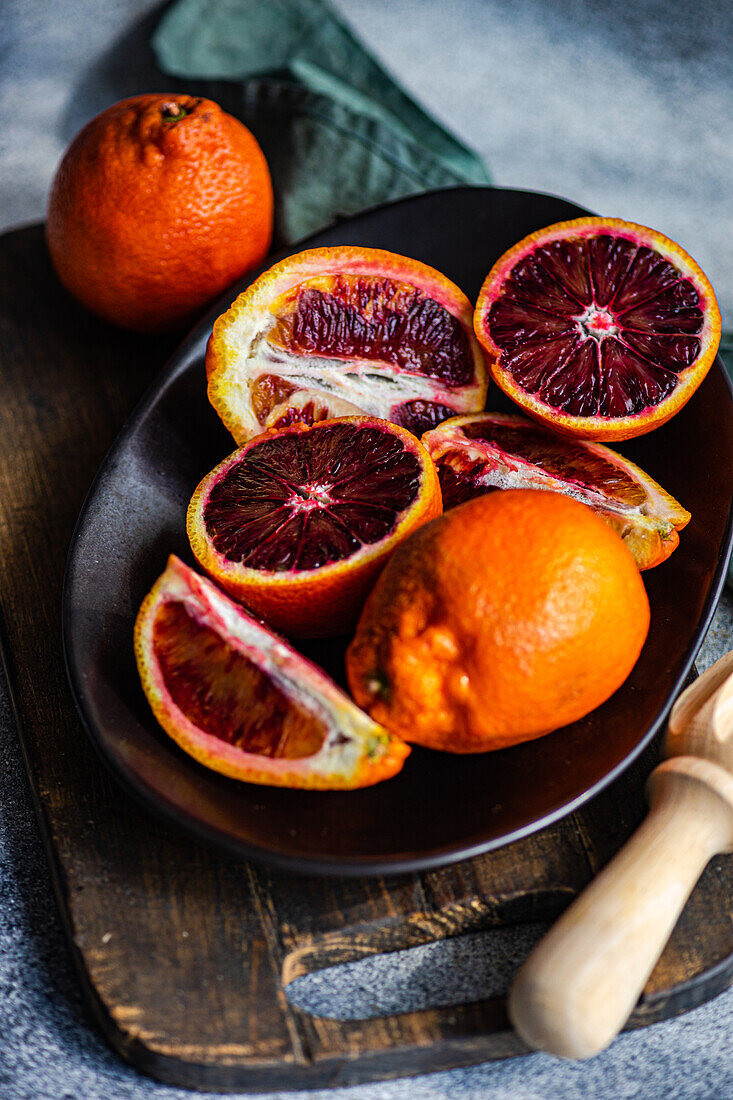 Fresh blood oranges sliced and displayed on a dark wooden plate, capturing their vibrant colors and juicy texture