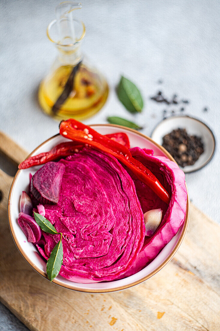 A bowl of vibrant fermented cabbage mixed with beetroot, spicy red pepper, and garlic, presented on a wooden surface.