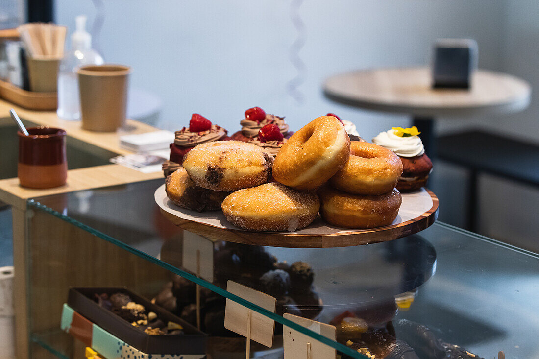 Various vegan sweet donuts and cakes on wooden tray placed on counter in bakery