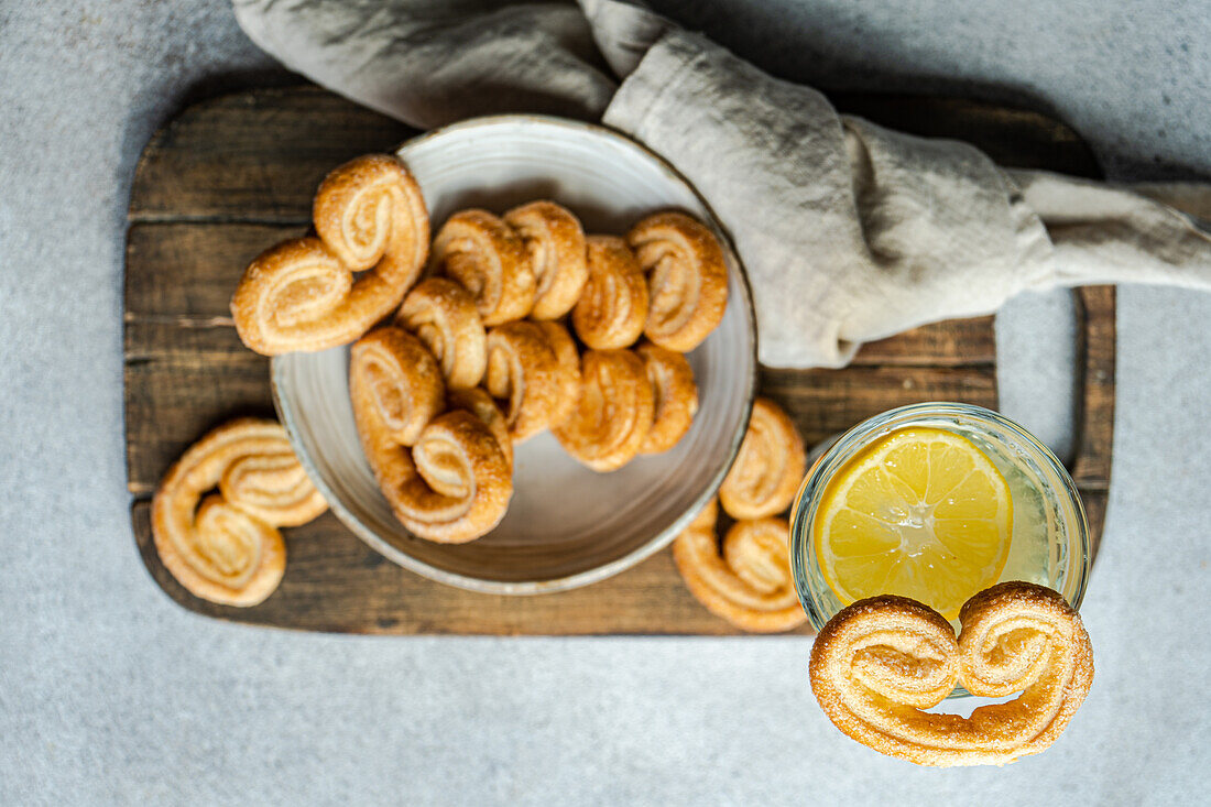 Palmiers oder Elefantenohren, Blätterteigplätzchen in der Schale auf dem Betontisch an einem sonnigen Tag