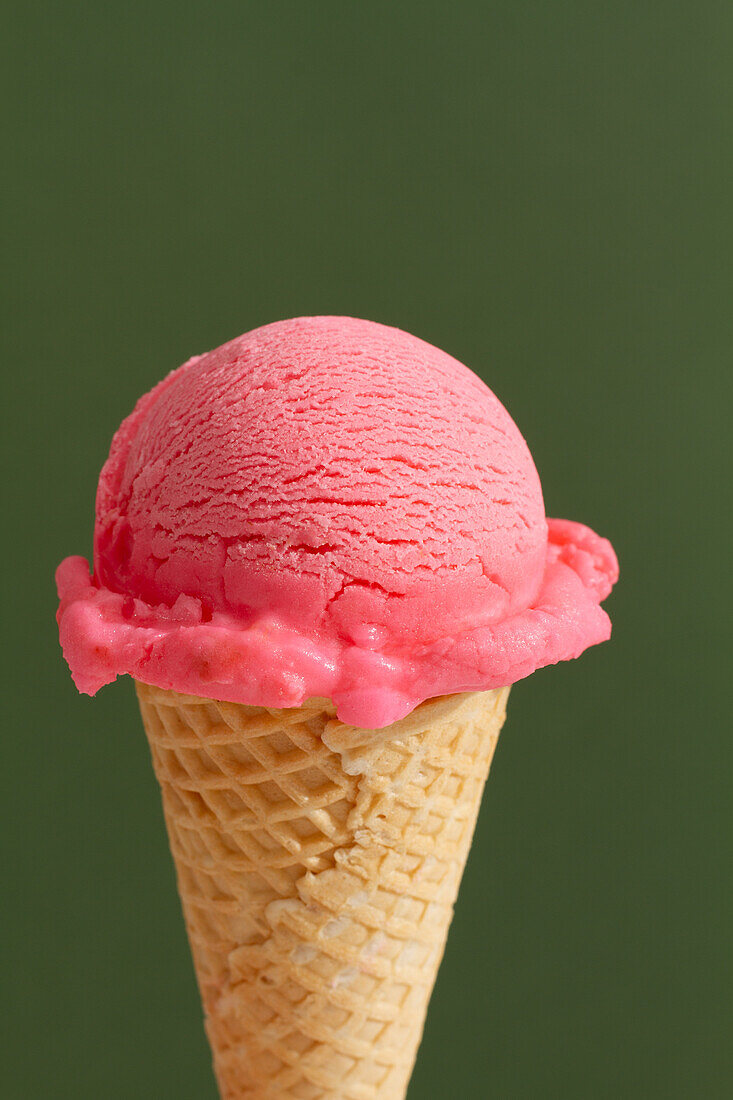 Scoop of strawberry ice cream on a cone in green background