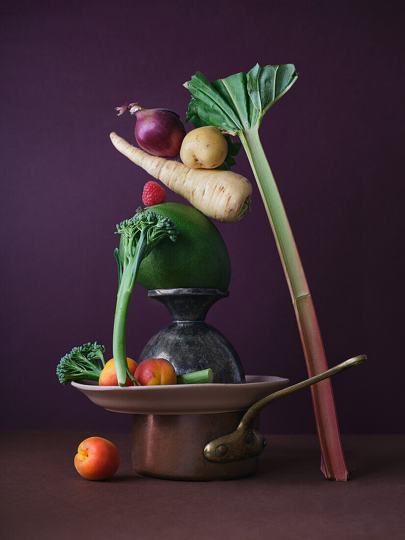 A creative and balanced arrangement of fresh vegetables, including broccoli, onion, carrots, and rhubarb, displayed in an antique kitchen setup