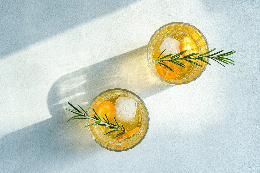 Sommercocktail Wodka mit Tonic und reifen Kumquat-Fruchtscheiben im Glas auf Steintisch von oben