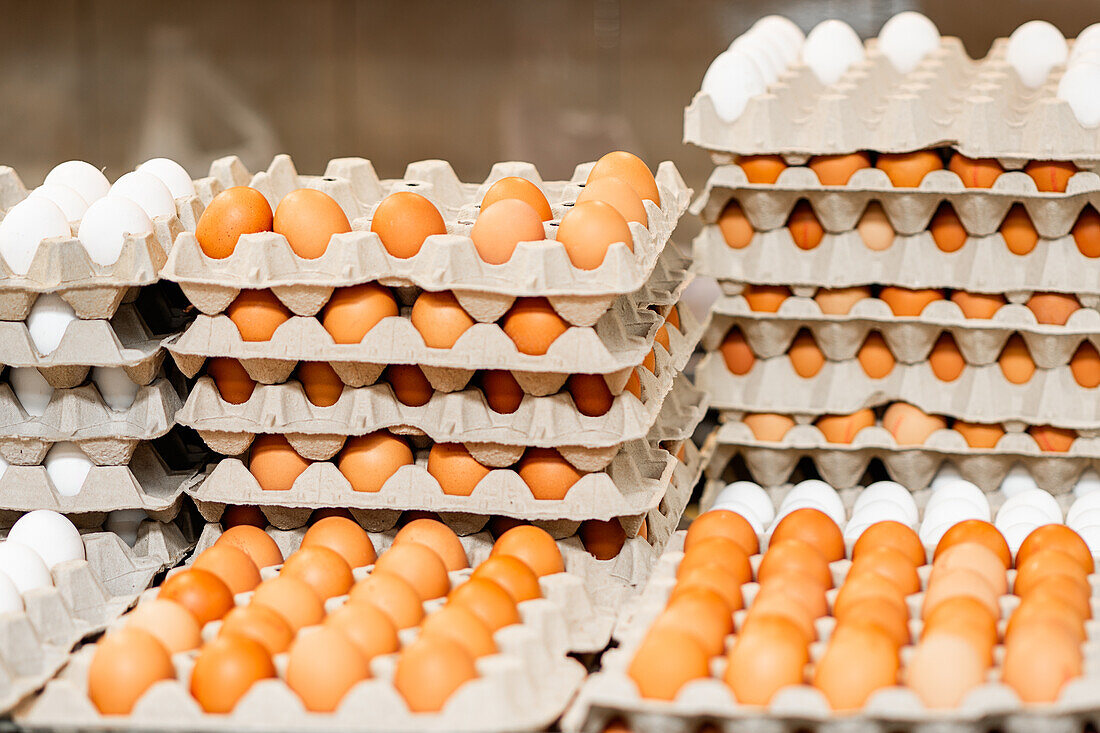 Stacked egg cartons filled with white and brown eggs on display, showcasing poultry farm produce ready for sale