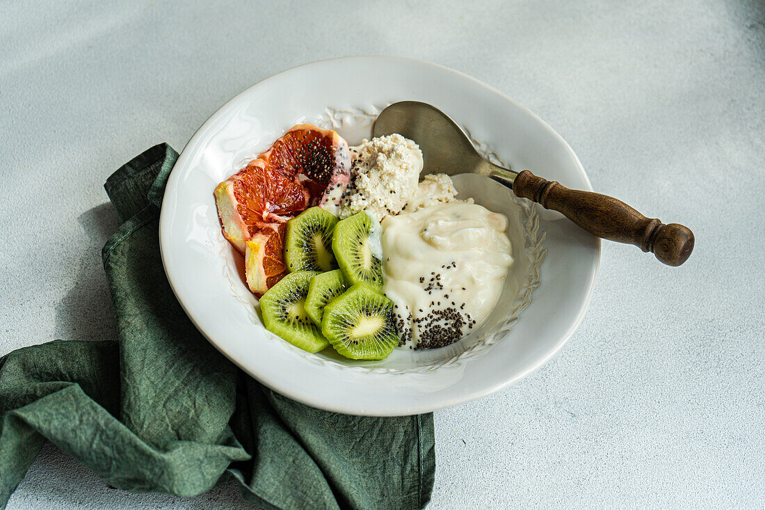 Beginnen Sie Ihren Tag mit dieser gesunden Schüssel mit Naturjoghurt, Hüttenkäse, Chiasamen und frisch geschnittenen Kiwis und sizilianischen Orangen