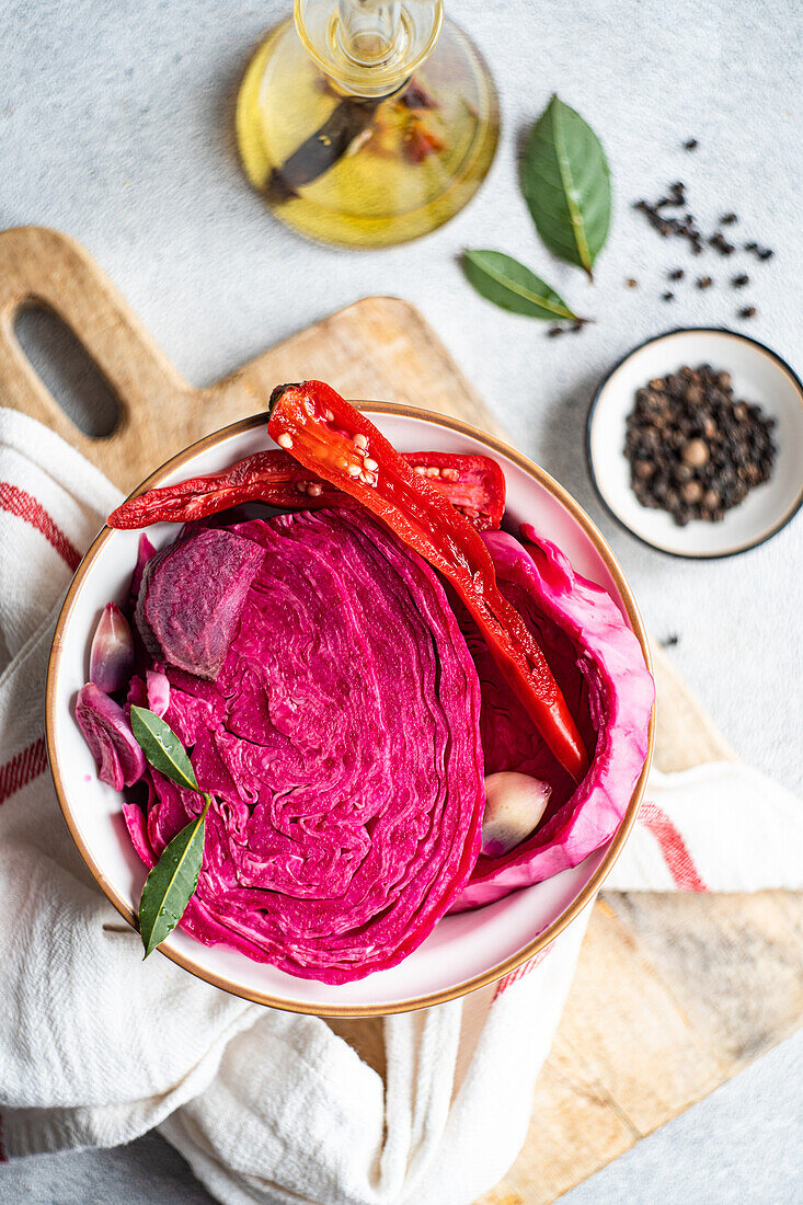 Eine Schüssel mit farbenfrohem fermentiertem Kohl, gemischt mit Scheiben von Roter Bete, würzigem rotem Paprika und ganzen Knoblauchzehen, die einen Kontrast von Texturen und Aromen einfangen.