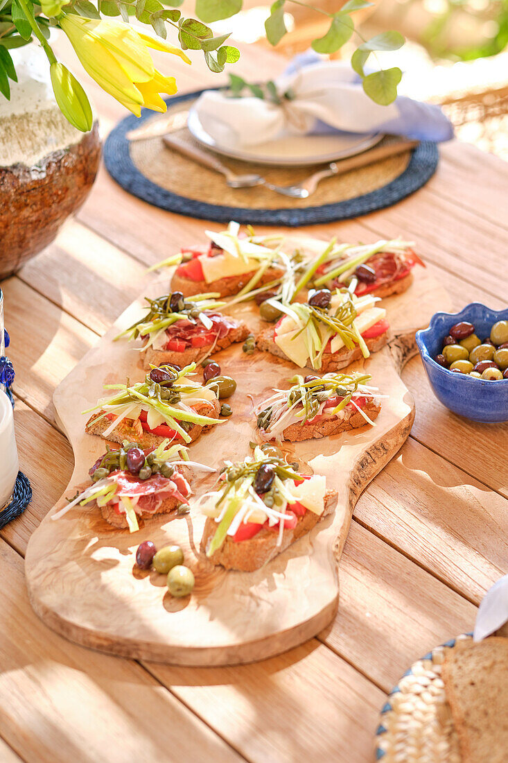 Offene Gourmet-Sandwiches auf einem Holzbrett mit lebendigem Rand, hervorgehoben durch das natürliche Morgenlicht auf einer Außenterrasse