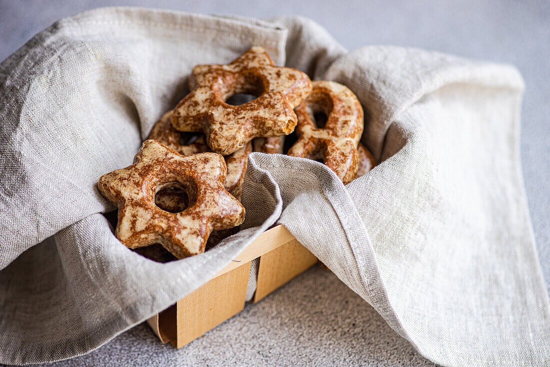 Freshly baked homemade gingerbread cookies in star shapes, nestled in a linen cloth inside a rustic wooden box.