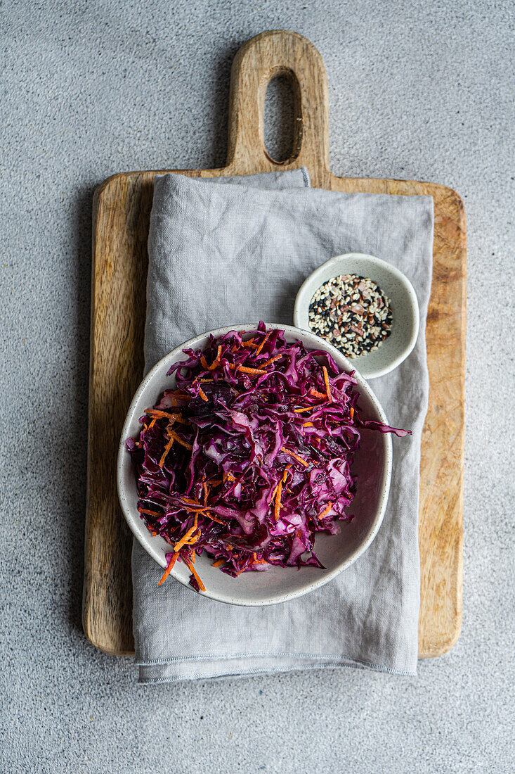 Delicious and nutritious lunch featuring a fresh red cabbage and carrot salad accompanied by boiled bulgur, served on a rustic wooden board