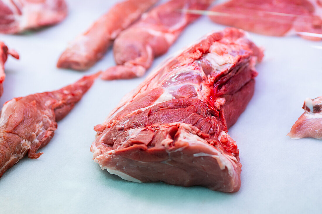 Various cuts of raw meat of veal displayed on light blue kitchen paper, showcasing textures and quality for culinary preparations