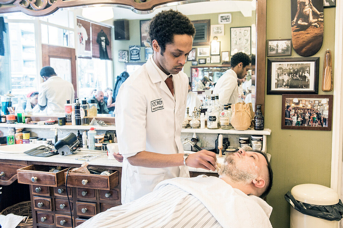 Professioneller Barbier und Haarschneider bei der Rasur seines Kunden im Schorem Barber Shop am Nieuwe Binnenweg, Rotterdam, Niederlande.