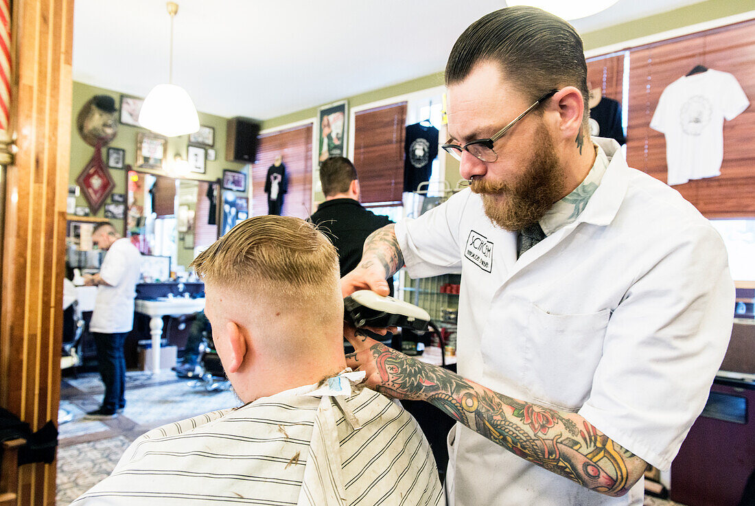 Professioneel barbier verzorgt het haar van een van zijn mannelijke klanten in de barbershop.