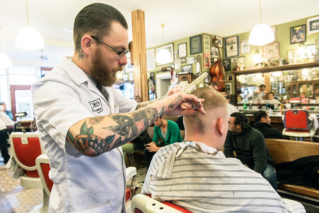 Ein professioneller Barbier verzorgt das Haar eines seiner Klienten im Friseursalon.