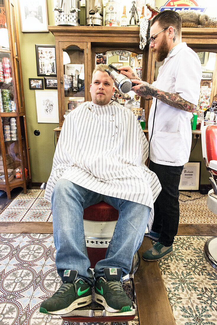 Professioneel barbier verzorgt het haar van een van zijn mannelijke klanten in de barbershop.