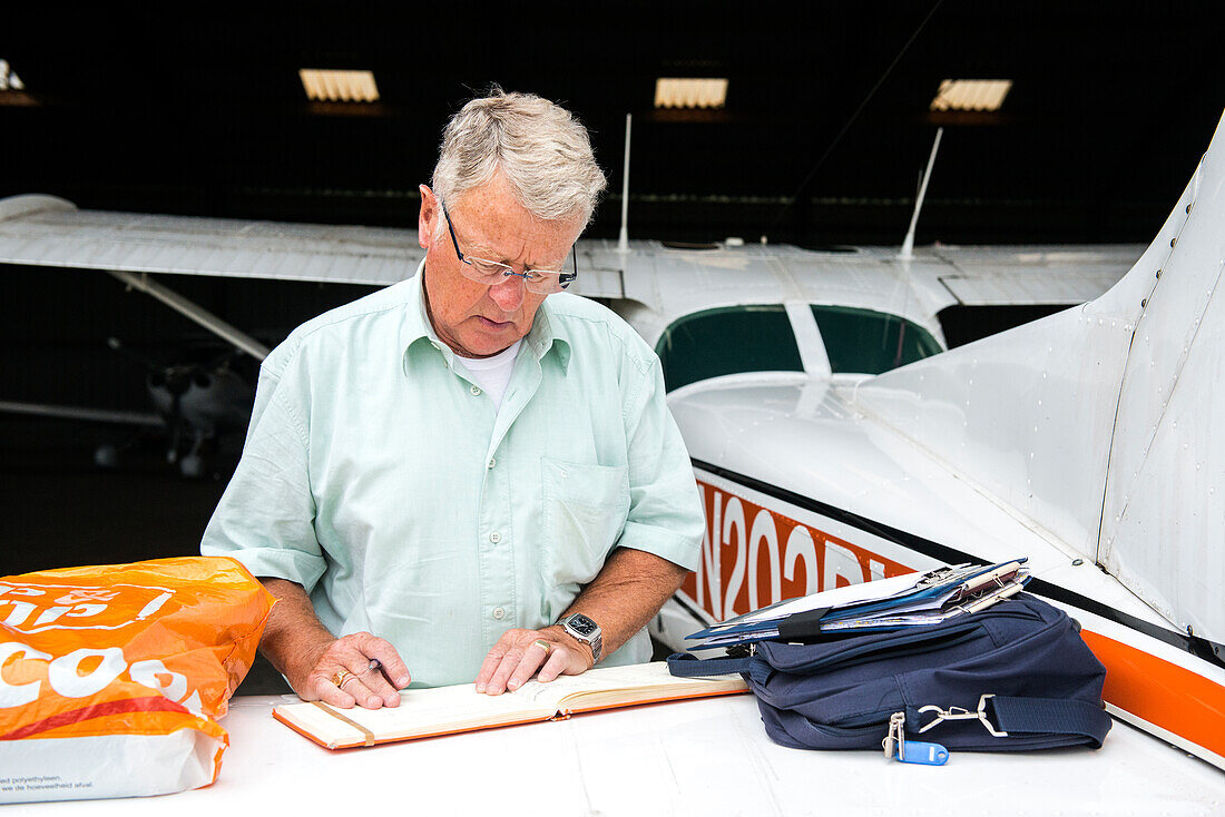 Flugplatz Seppe, Oudenbosch, Niederlande. Ehemaliger Pilot beim Ausfüllen seines Flugbuchs.