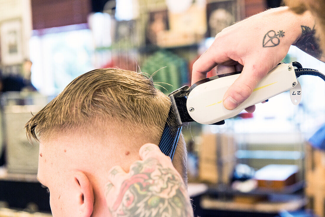 Professioneel barbier verzorgt het haar van een van zijn mannelijke klanten in de barbershop.