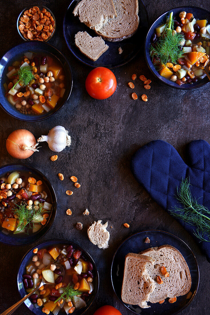 Bowls of Sardinian-style minestrone longevity soup served with sourdough bread. Top down flatlay with negative space.