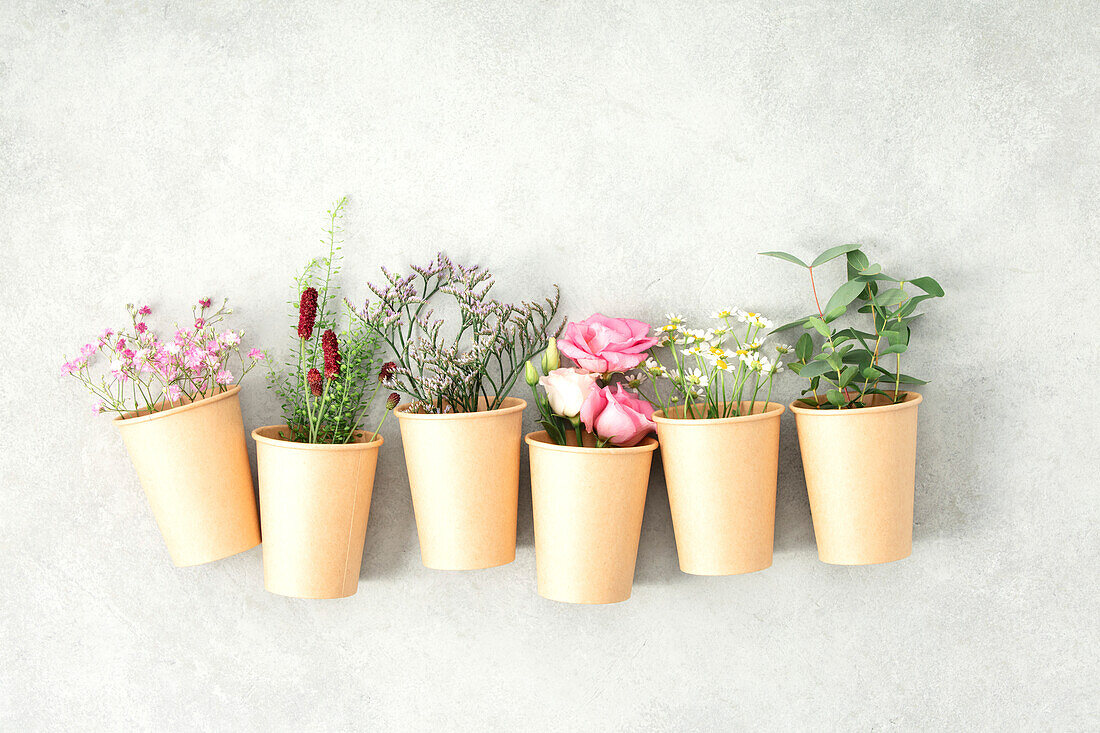 Paper cups with spring flowers, zero waste concept, flat lay banner