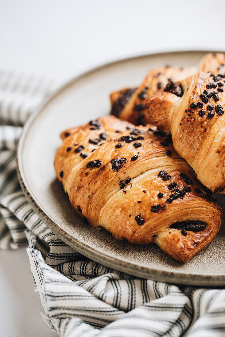 Schokoladencroissants auf Teller und weißem Hintergrund