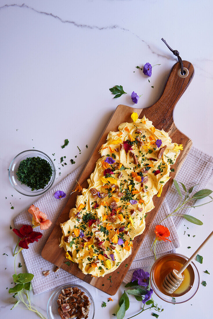 Butterbrett mit Kräutern, Pekannüssen und essbaren Blumen mit Kopierbereich.