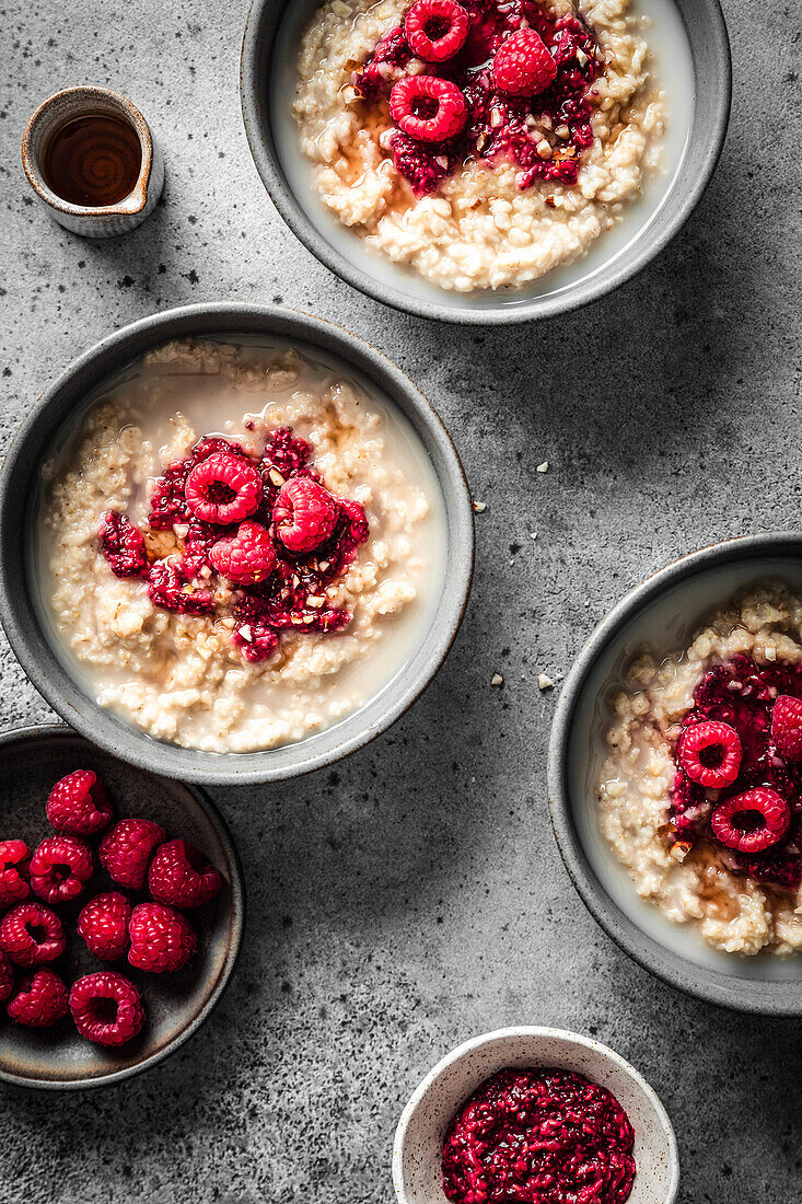 Breakfast Oatmeal and raspberry porridge bowls on grey surface