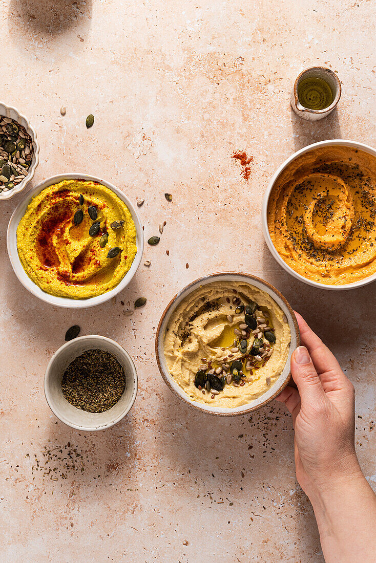 Bowls of chickpea hummus with hand