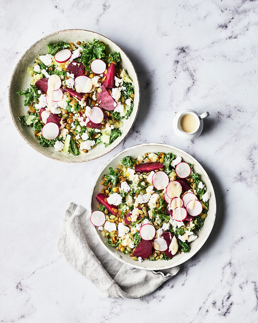 Two bowls of beetroot and kale salad on a marble slab