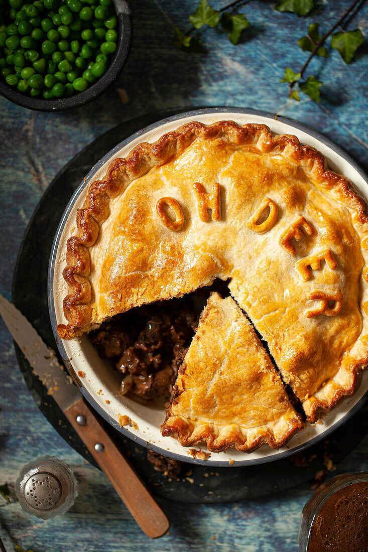 Venison Pie made with shortcrust pastry. Two slices have been cut, one of which has been removed from the baking tin.