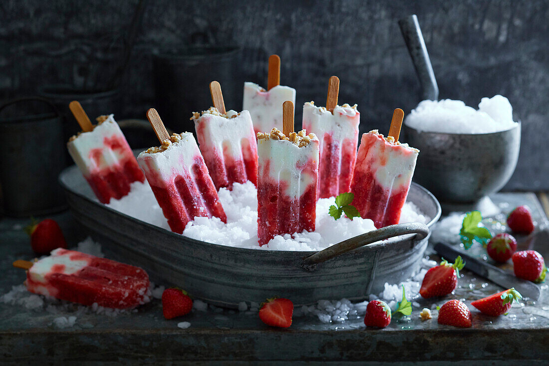 Homemade strawberry yoghurt ice cream on crushed ice in a metal bowl on a grey metal background