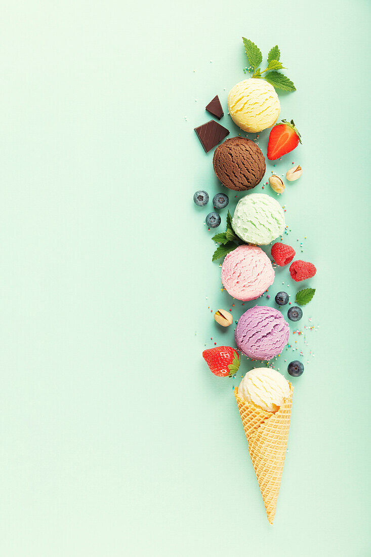 Fliegende Eiskugeln und Zutaten auf pastellfarbenem hellblauem Hintergrund. Sommerliches Minimal-Konzept