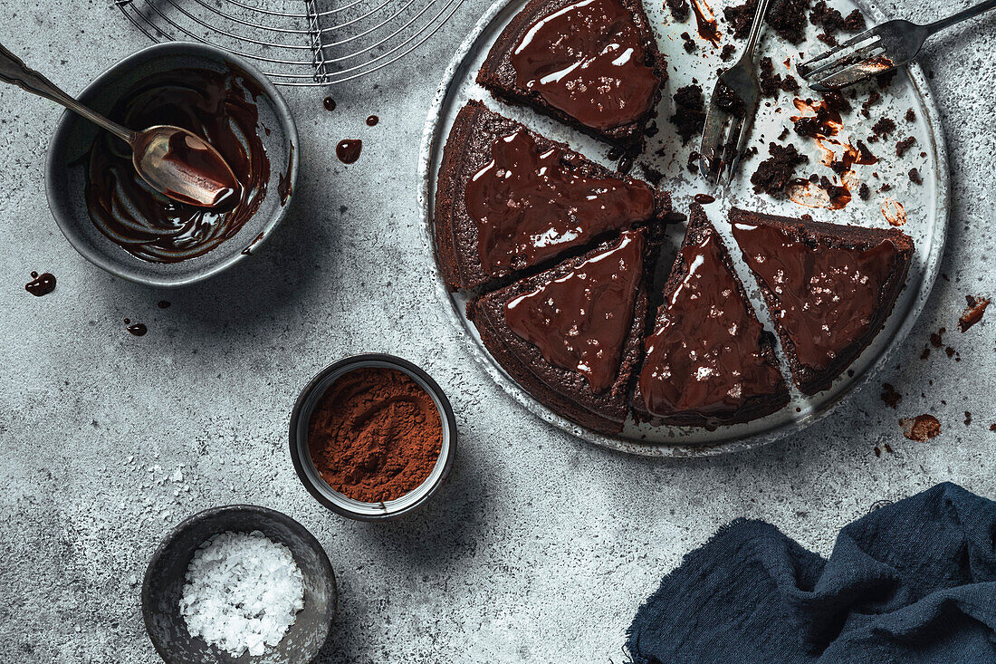 Chocolate cake with chocolate icing and melted chocolate on a grey background.