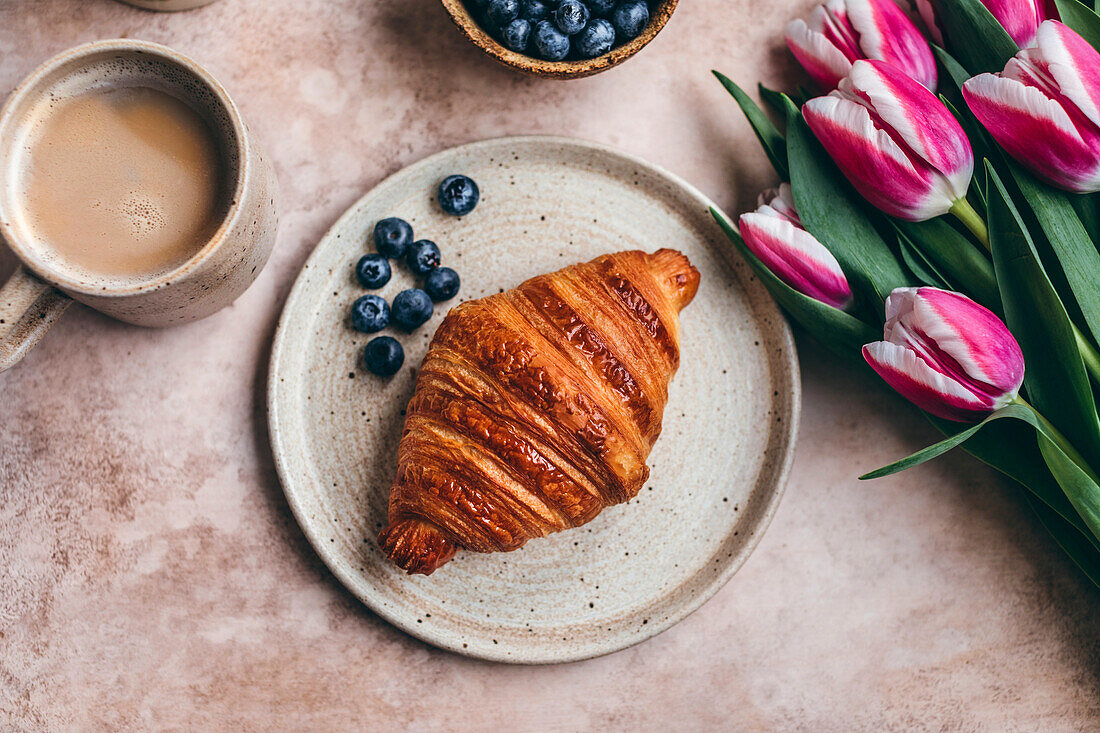 Croissant und Blaubeeren auf einem Keramikteller