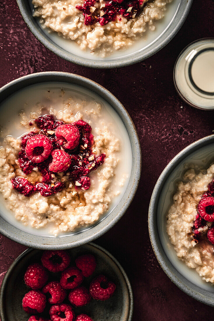 Breakfast oatmeal porridge with raspberries on a red surface