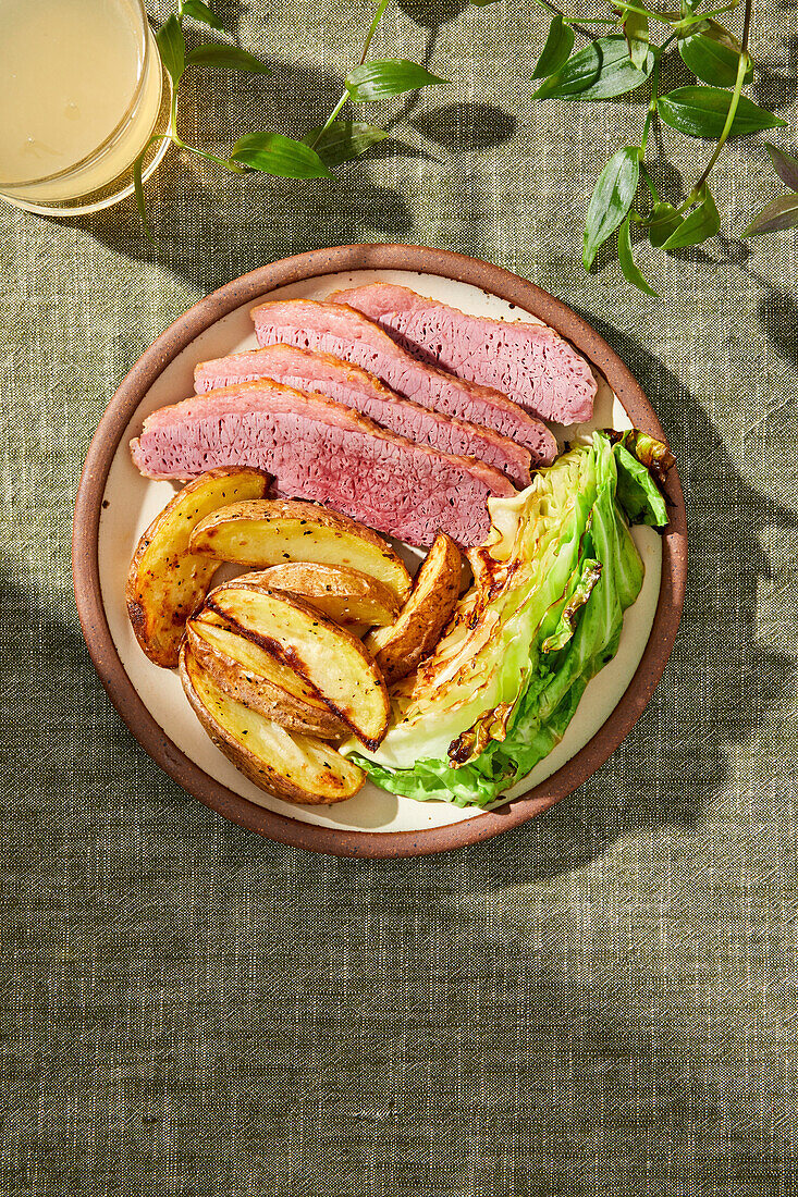 Corned Beef, Roasted Potatoes and Cabbage Meal on a green background