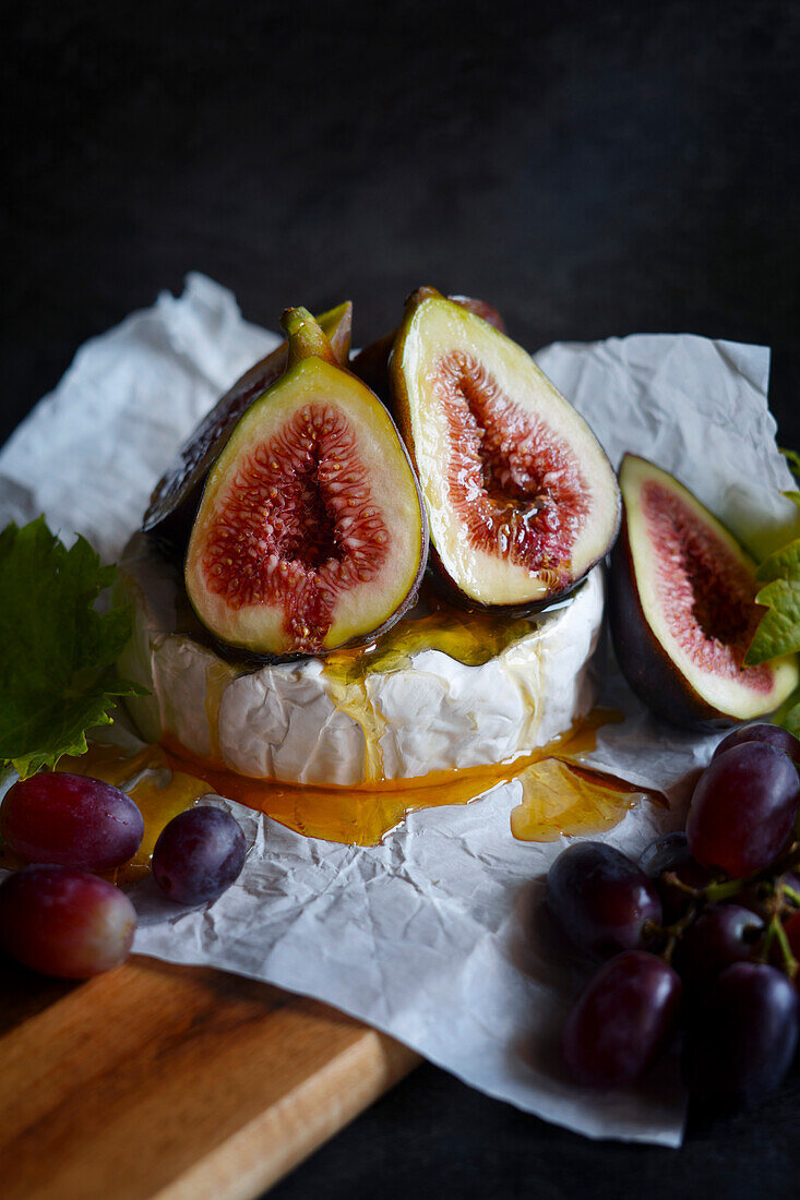 Brie cheese with figs, honey and grapes, close-up.